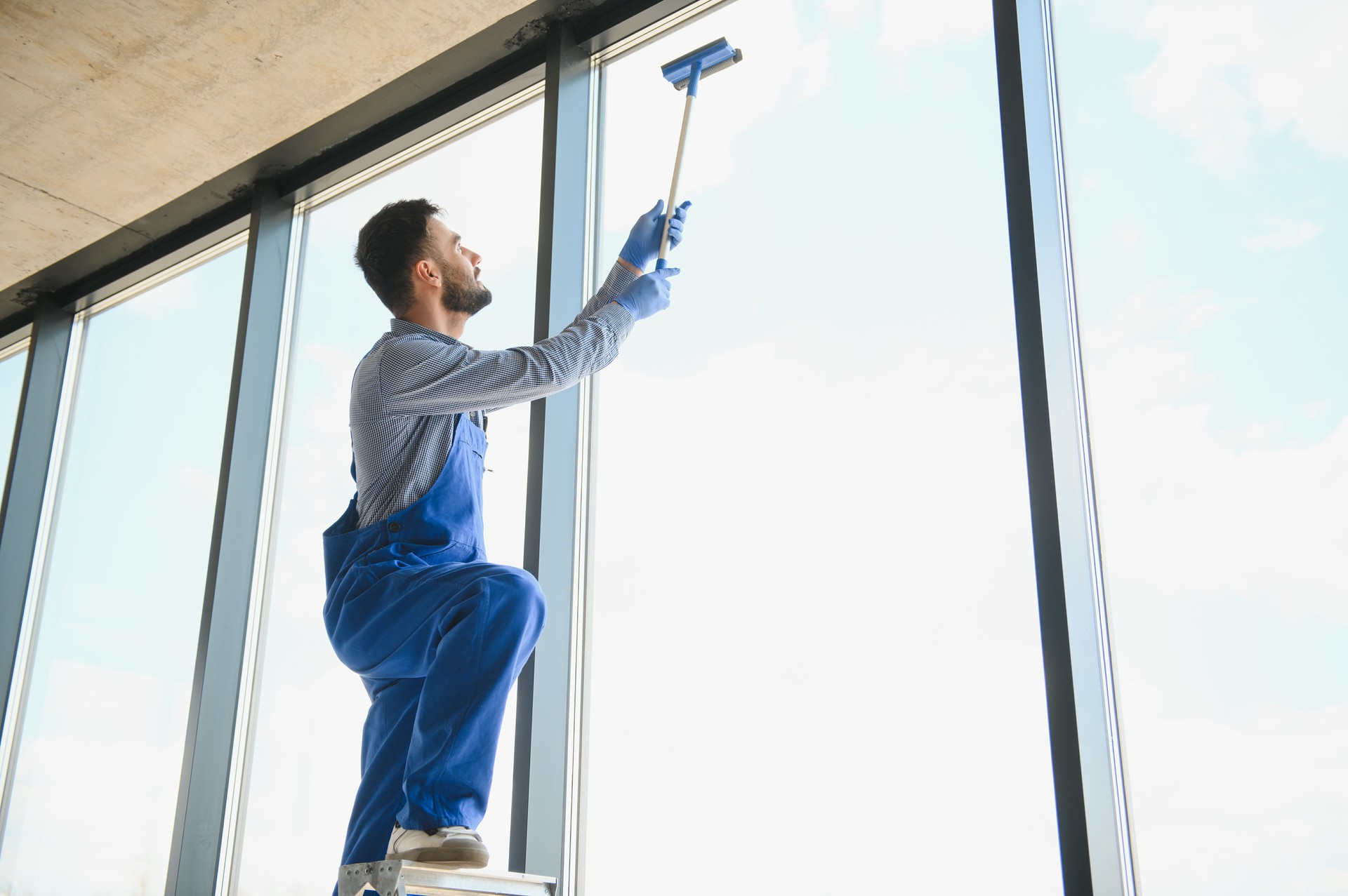 Young man cleaning window in office